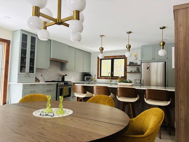 Cuisine vert sauge avec îlot, luminaires dorés et table ronde