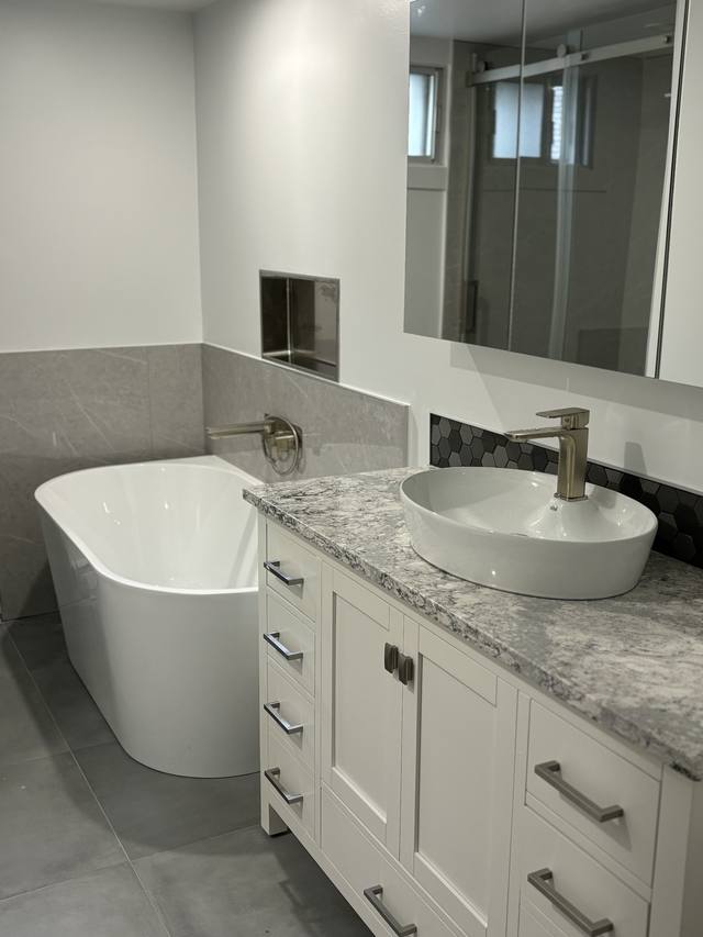 Baignoire autoportante et vanité blanche avec vasque et comptoir de marbre