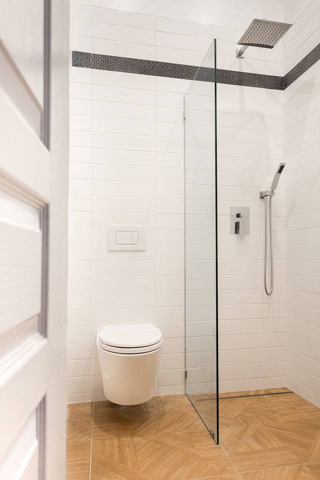 Salle de bain blanche avec douche vitrée et toilette suspendue