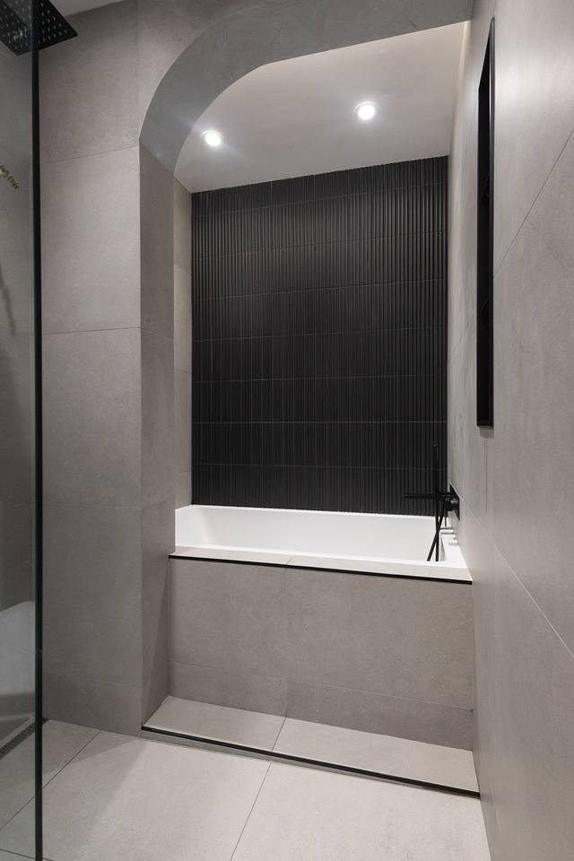 Alcôve en arche et baignoire derrière la paroi vitrée