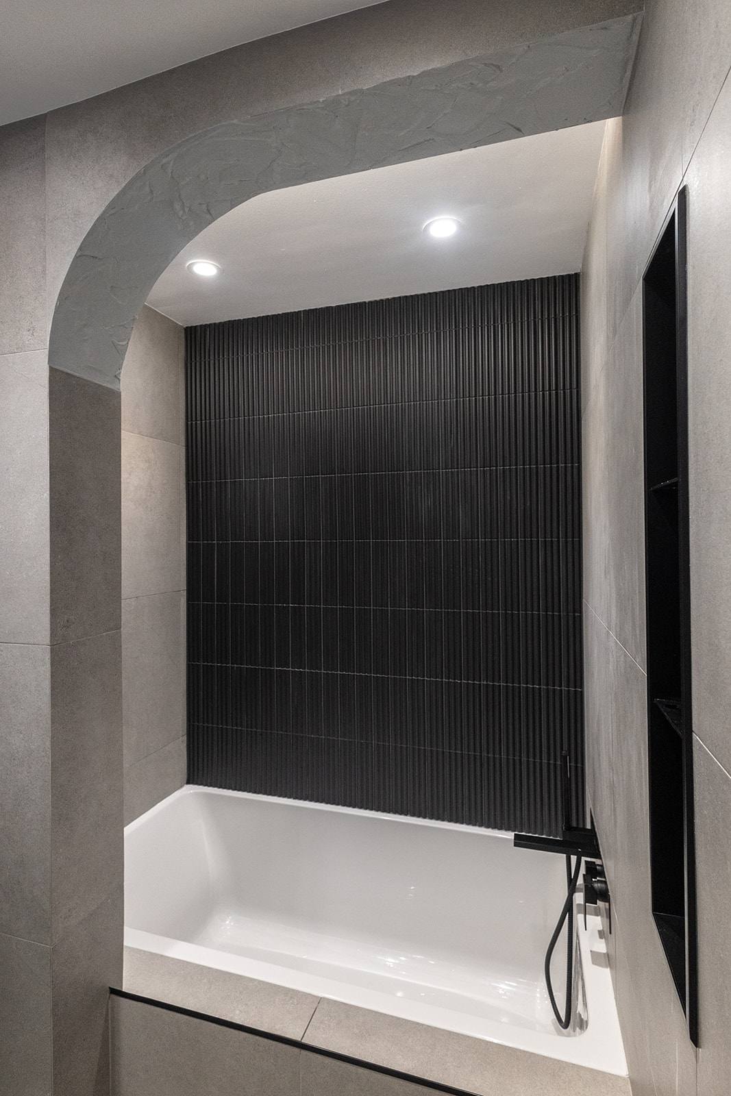 Baignoire dans une alcôve en arche avec tuile cannelée noire