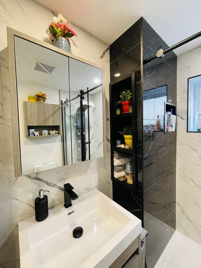 Lavabo blanc et mur de douche noir avec robinetterie noire