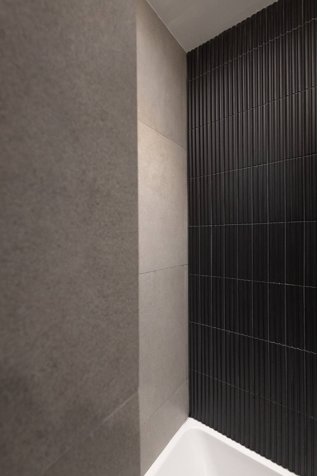 Salle de bain habillée de tuile cannelée noire et de céramique grise